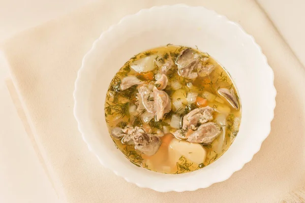 Beyaz bir kase Tavuk sakatat çorbası. Üstten görünüm.