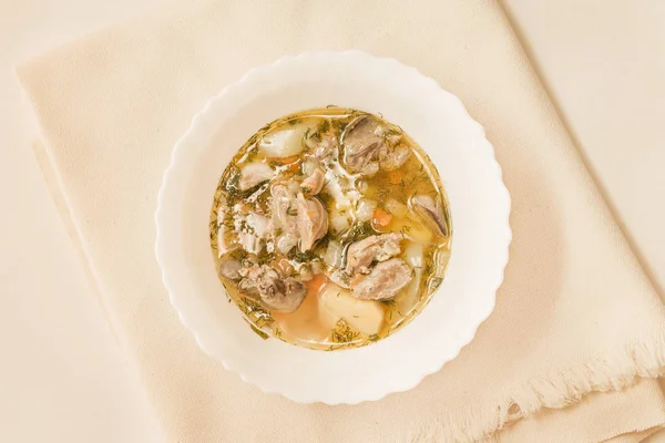 Beyaz bir kase Tavuk sakatat çorbası. Üstten görünüm.