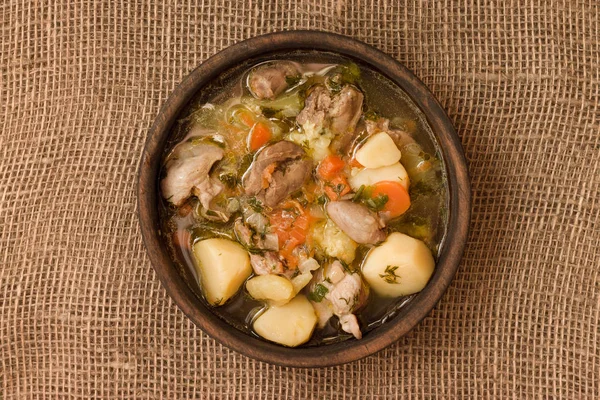 Tavuk sakatat ve ahşap kase sebze çorbası. Üstten görünüm.