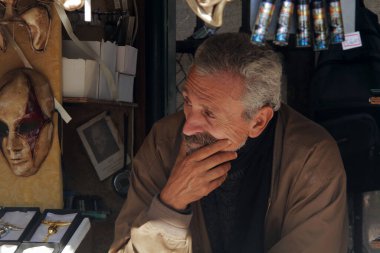 Venedik, İtalya - 07 Ekim 2017: Yaşlı bir adam - küçük bir Venedik mağazasında bir satıcı - düşünceli bir şekilde yüzünü çevirir.