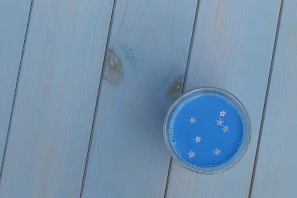 Blauer Matcha-Latte aus Anker mit Vergissmeinnicht in Glasschale auf blauem Holztisch stehend — Stockfoto