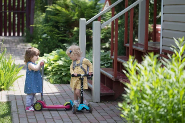 Deux jolies filles tout-petits avec scooters s'amuser à la campagne dans la journée ensoleillée d'été — Photo