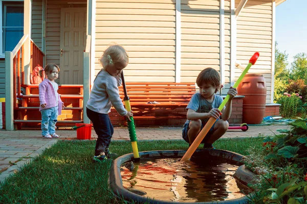 Les enfants jouent dans le jardin sur le fond de la maison de campagne. — Photo