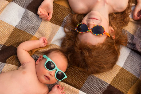 两个姐姐- -学龄前女孩和婴儿戴着太阳镜躺在海滩上 — 图库照片