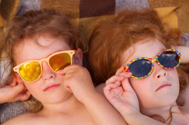 Sahilde güneş gözlüğü takmış kızıl saçlı iki kız kardeş.