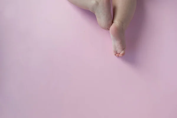 Açık pembe arka planda şirin tombul yeni doğmuş bebek bacakları. Boşluğu kopyala
