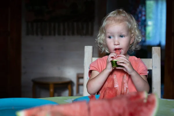 小漂亮姑娘，金发卷曲，坐在厨房里吃西瓜 — 图库照片