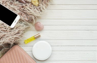 Beyaz ahşap arka planda telefon, el çantası, kozmetik ürünleri ve mineralleri olan kadınlar. Güzellik kavramı, kendini sevme, özgüven ve iç huzur..