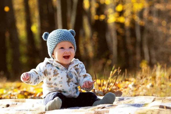 Petit bébé mignon dans un chapeau drôle avec des oreilles assises dans le parc en automne ensoleillé jour — Photo