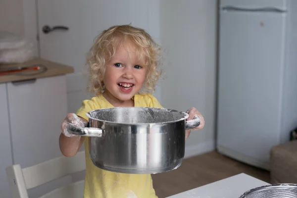 厨房里的金发卷曲小女孩 手里拿着一个大金属罐 上面还挂着点缀 女孩开心地笑着 面粉在她的手上 家庭时间概念 — 图库照片