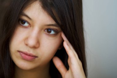 Düşünceli, kahverengi gözlü, esmer bir kadının portresi.