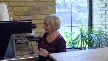 Olgun kadın kahve dükkanında ziyaretçi için kahve yapayım