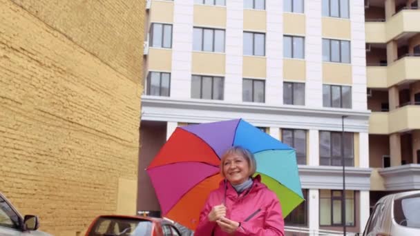 Senior woman with colorful umbrells meet someone at the street — Stock Video