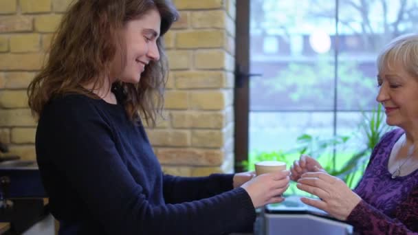 Barista ger en kopp med kaffe till en äldre kvinna — Stockvideo