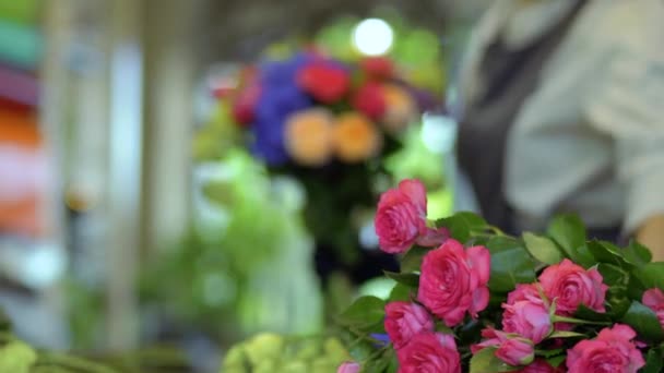 Bloemist bloemboeket op onscherpe achtergrond van rozen maken — Stockvideo