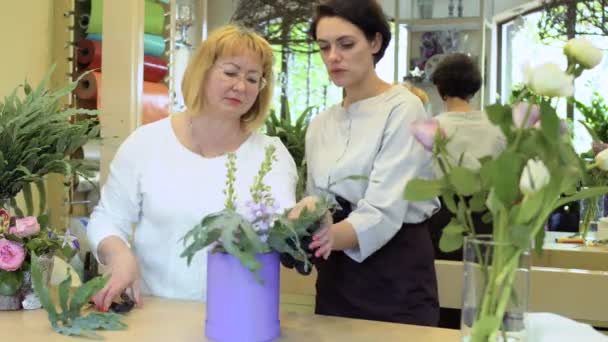 Флорист с ассистентом создает цветочную композицию — стоковое видео