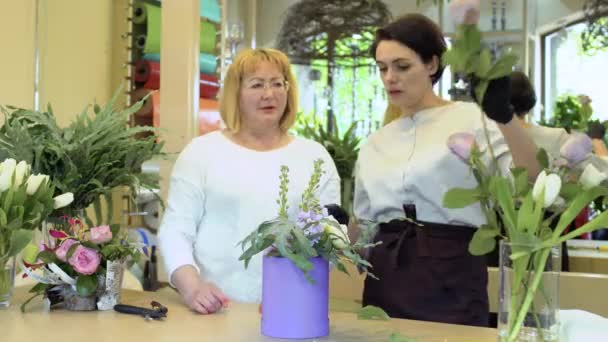 Dos floristas hacen la composición de flores en la tienda de flores — Vídeos de Stock