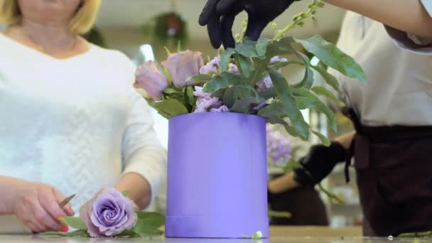 Квітник з помічником робить квіткову композицію з трояндами всередині коробки — стокове відео