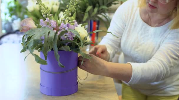 女性は花の組成とボックスの周り装飾ロープを結ぶ 花屋を飾る装飾的な要素を持つ花の組成 Prores コーデック — ストック動画