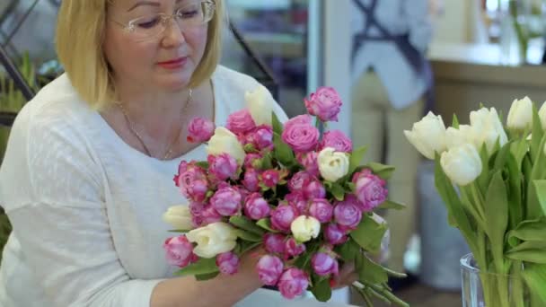 成熟した女性の身に着けている眼鏡はバラとチューリップの美しい花束を保持します — ストック動画