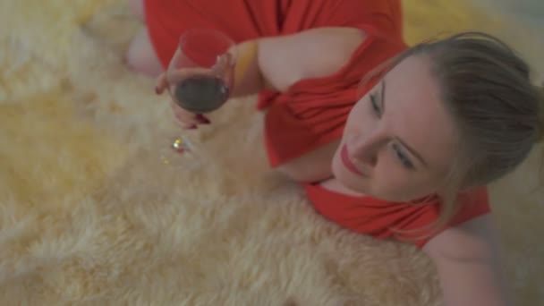 Ung kvinna ligger på fluffig matta och berätta något till kamera — Stockvideo