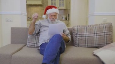 Noel Babalar şapkalı yaşlı adam evde kanepe gündeminde okur