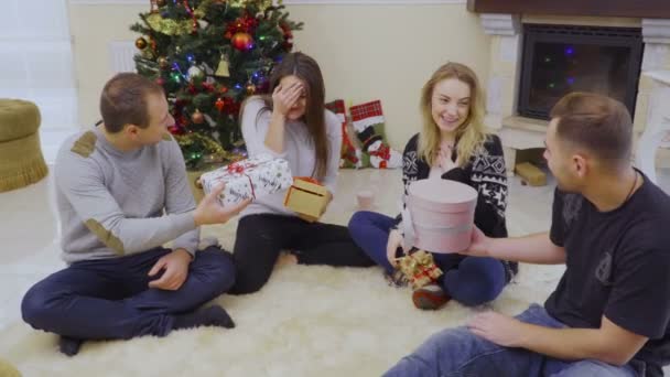 Vier junge Freunde tauschen Weihnachtsgeschenke aus — Stockvideo