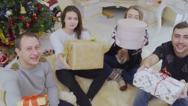 Feliz gente joven da regalos de Navidad a la cámara — Vídeo de stock