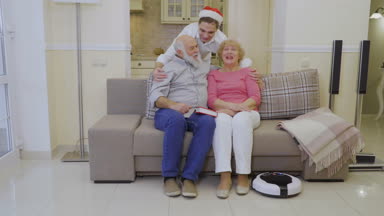 Genç adam Santas şapkalı dedesi hugs, mutlu bir aile başparmak ortaya çıktı