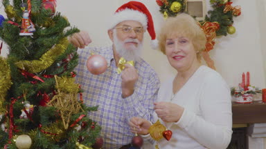 Mutlu çiftimiz Noel ağacı Yılbaşı önce süsleyin. Kadın çift fotoğraf çekmek. Olgun insanlar christams oyuncaklar Noel ağacı ve gülümseyen asmak. Üst düzey insanlar, theie tatil birlikte geçirmek