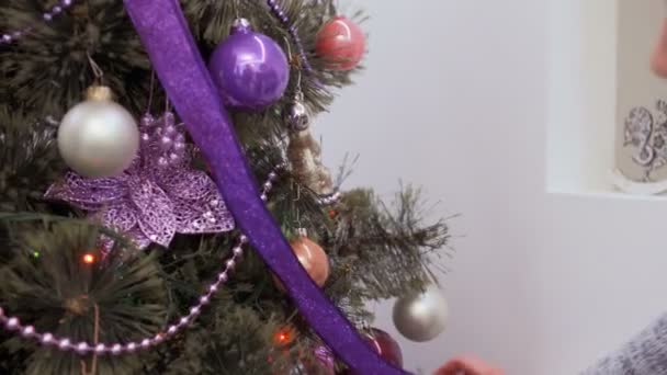 两个女朋友在家装饰圣诞树 漂亮女孩挂玩具 把五颜六色的花环放在冷杉树上 两个年轻的姐妹准备寒假和有一个美好的时光 — 图库视频影像