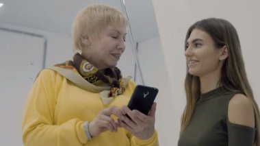 Kadınlar Smartphone'da fotoğraflara bak. İki fotoğrafçılar Fotoğraf yaptıktan sonra atış kompozisyonu tartışmak. Photostudio çalışmalarında profesyonel tasarımcılar.