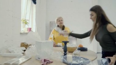 Genç ile Olgun kadın kadın photoset için tablo hazırlamak. Fotoğrafçılar beyaz fotoğraf stüdyosunda çalışıyor. 