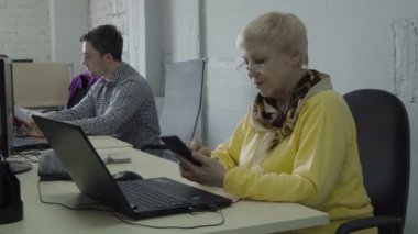 Emekli kadın çalışmaları sırasında ofiste telefonunu kullanın