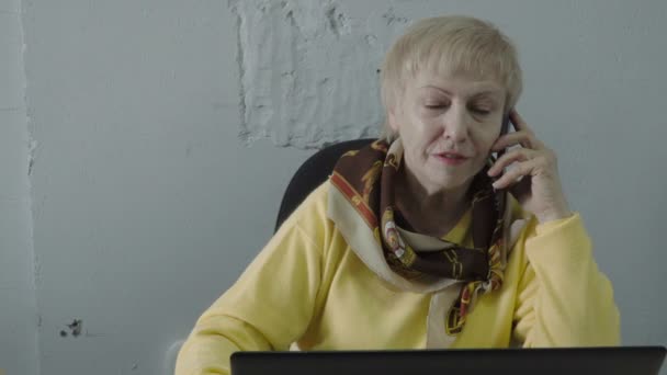 Pensionerad kvinna prata på telefon på kontoret — Stockvideo