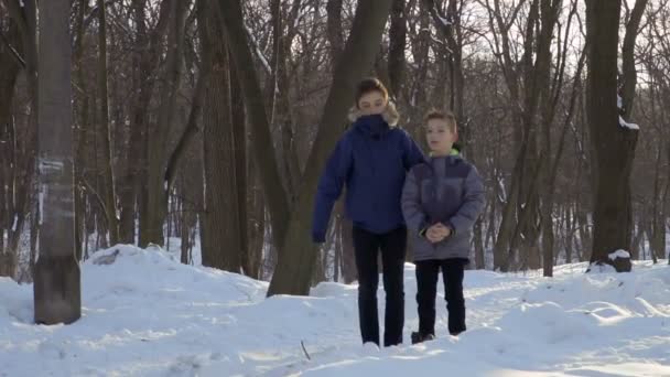Два мальчика смотрят на летающего голубя в зимнем парке, замедленная съемка — стоковое видео