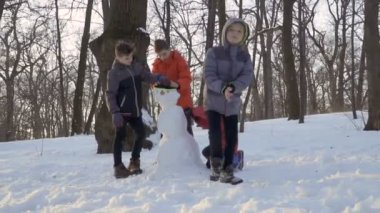 Serin küçük çocuk kardan adam yapma bitmiş ve uzak çocuklar yavaş çekimde gidin