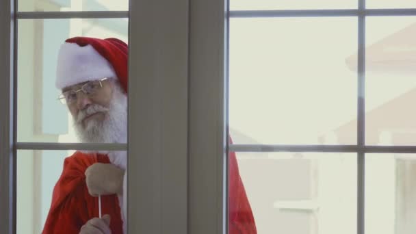 Санта Клаус Красном Костюме Пакетом Подарков Стучит Окно — стоковое видео