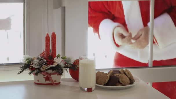 サンタ クロースは家の中 ガラスを通して見るウィンドウに来ています テーブルの上でそれを味わうに非常にエキサイティングな祖父にはクッキーとミルクが見ています — ストック動画