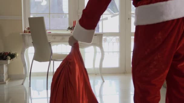 圣诞老人来到屋内 老人把带礼物的红书包放在地板上 带着饼干走到餐桌旁 小男孩偷偷溜了起来 非常小心地偷了包 — 图库视频影像