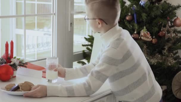 Rapazinho Põe Biscoitos Mesa Copo Leite Criança Senta Cadeira Branca — Vídeo de Stock