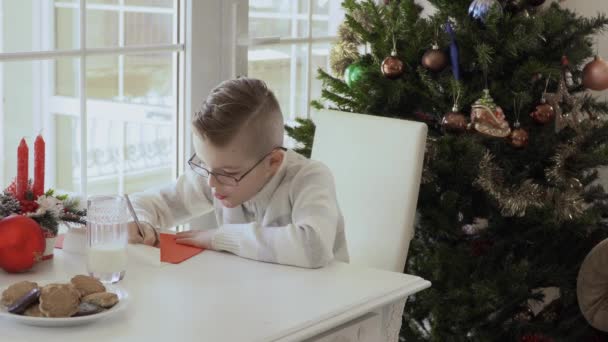 Niño Feliz Sentado Cerca Ventana Escribe Carta Santa Papel Rojo — Vídeo de stock
