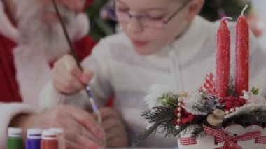 Noel Baba ve çocuk birlikte iki kırmızı mumlar brançlardan köknar ağacı, sahte kar, kar tanesi ve kurdele ile süslenmiş arka planda çizmek.