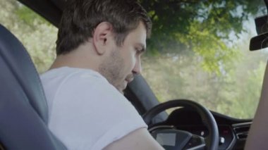 Genç adam arabanın içinde. Yakışıklı adam gülümseyerek ve Denetim Masası arıyorum. Ağır çekim.