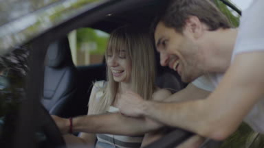 Yakışıklı genç kız yeni arabada bazı düğmeleri kullanmayı açıklar. Şaka ve gülerek aşk çift. Ağır çekim.