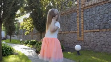 Güzel elbiseli güzel küçük kız ayağa bahçesinde çiçek sepeti bulunan yolda elinde. Kamera için poz ve saçları ile flört sevimli kız.