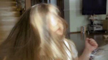 Kız uzun saçları çok hızlı bir şekilde hareket ettirin. Çok güzel çocuk büyük yumuşak oyuncak katta oturan eğlenceli.