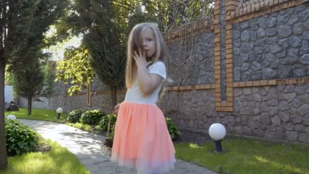스러운 드레스에 바구니 정원에서 경로에 귀여운 카메라 포즈와 그녀의 머리와 — 비디오