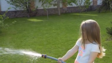 Küçük kız bir hortum çiçek yatağından su. Çok güzel çocuk yardım ailesi ile Bahçe işleri.