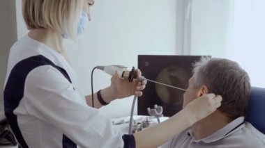 Doktor hasta kulak KBB teleskopla incelemek ve monitör ekranında bakın. Komuta sizde kontrol otolaryngologist modern kliniğinde kulağına.